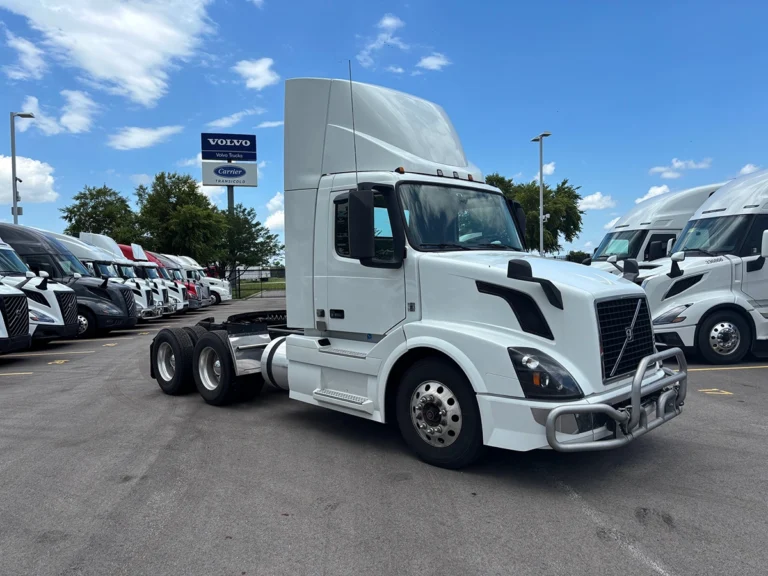 White 2017 Volvo VNR64T300 sleeper cab truck tractor, front driver-side view, parked at a dealership lot with other trucks in the background.