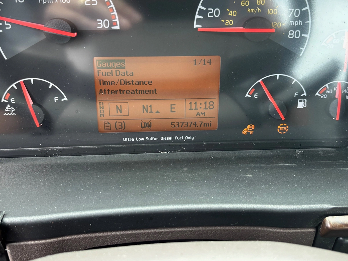 Close-up of the truck's dashboard display showing a menu with Gauges, Fuel Data, Time/Distance, and Aftertreatment options, and an odometer reading of 537,374.7 miles.