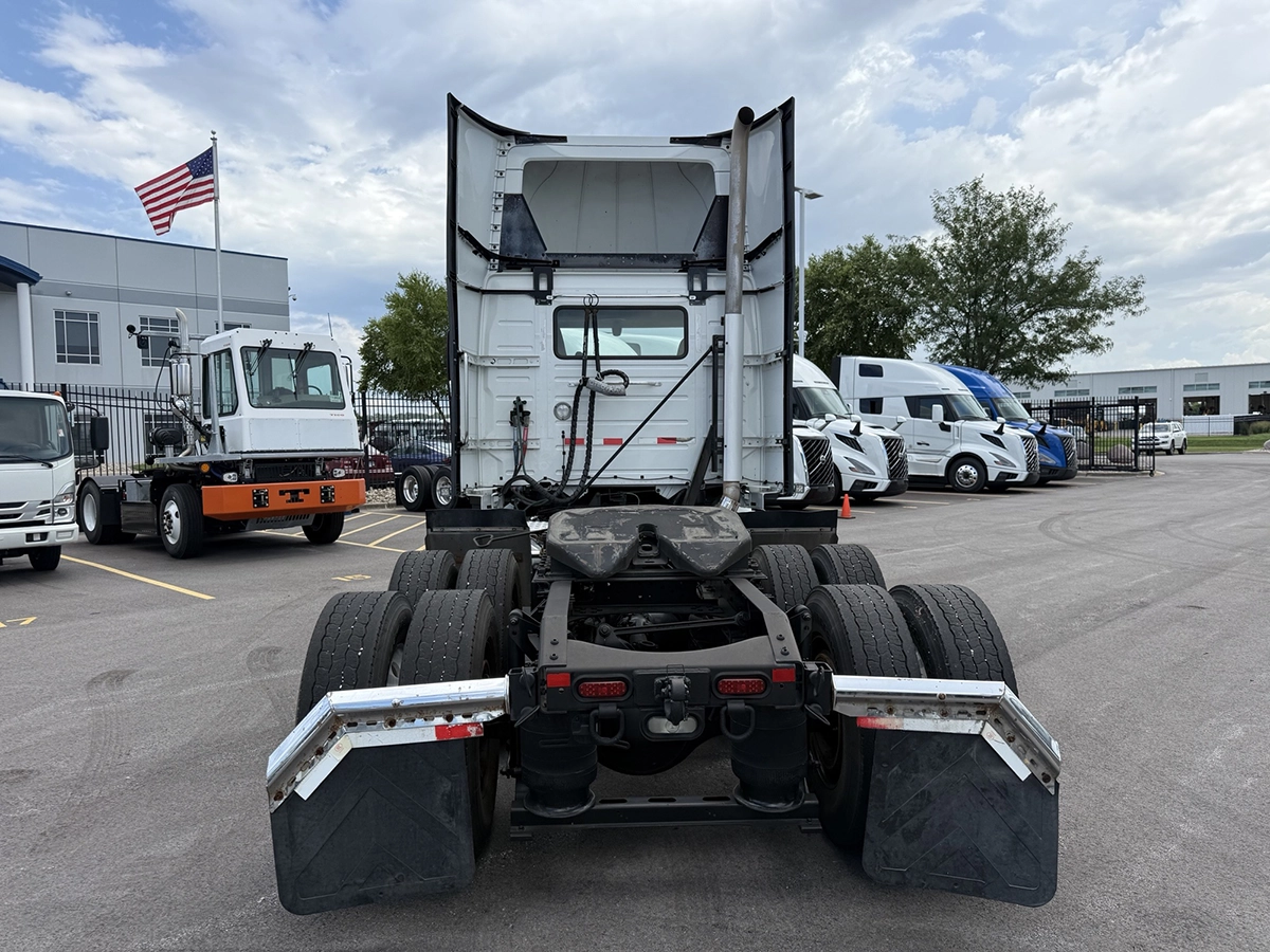 Straight-on rear view of the Volvo VNR day cab tractor showing the back of the cab, exposed frame rails, tandem rear axles, and mud flaps.