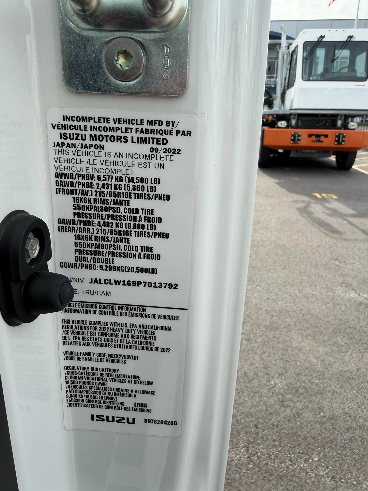 Close-up of the manufacturer compliance and specification sticker on the driver door jamb of a 2023 Hino S4 truck, listing weight ratings and emissions certification.