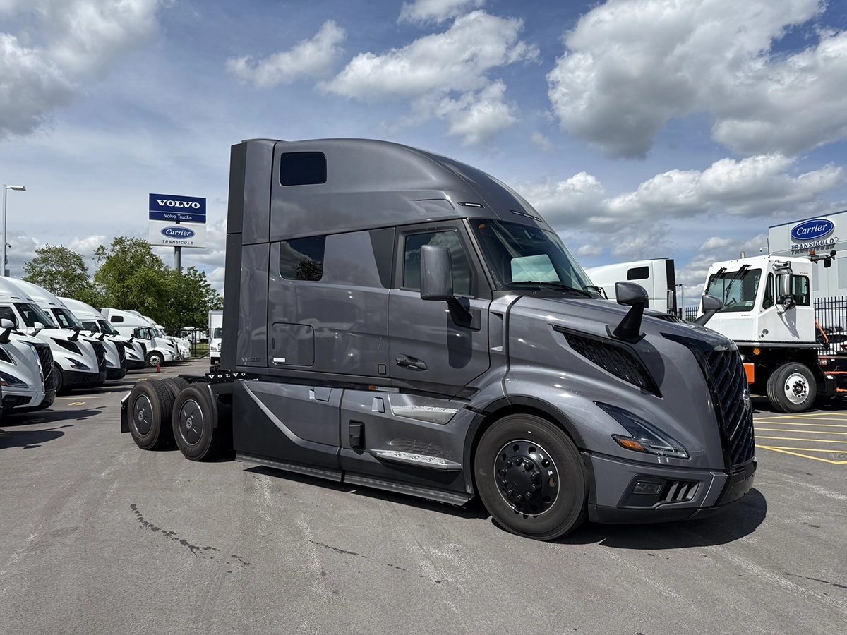 Front passenger side view of a gray 2025 Volvo VNL64T860 sleeper semi truck with a high-roof sleeper cab and tandem rear axles.