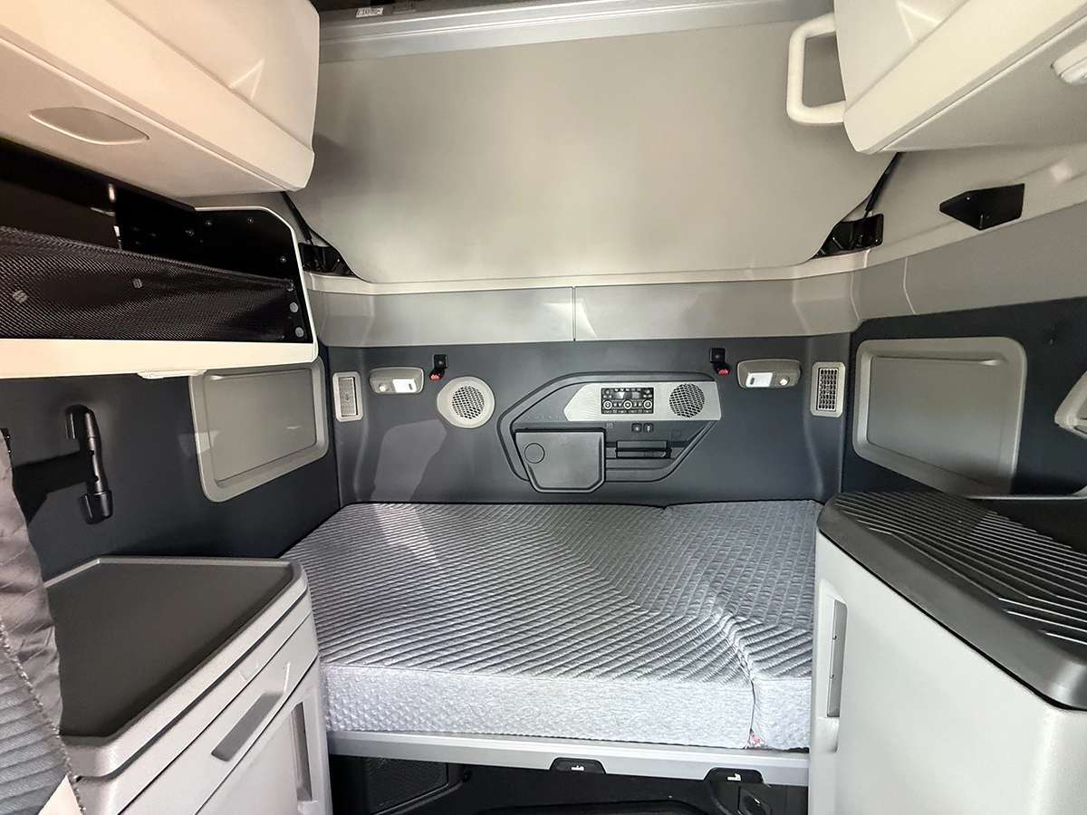 Rear driver side view of a gray 2025 Volvo VNL64T860 sleeper semi truck showing the aerodynamic cab extenders and tandem drive axles.