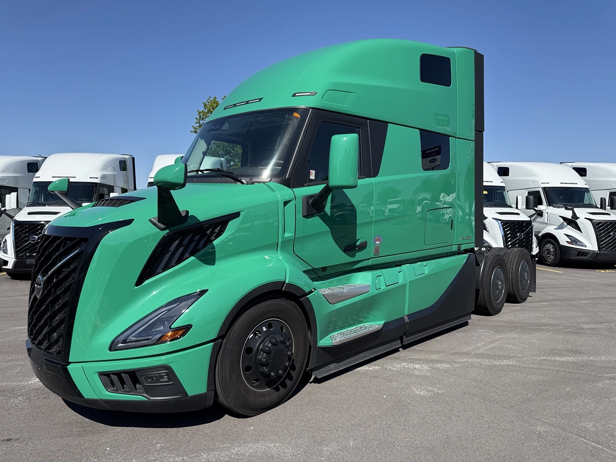 Front driver side view of a green 2025 Volvo VNL64T860 sleeper semi truck with a black grille and aerodynamic high-roof sleeper cab.
