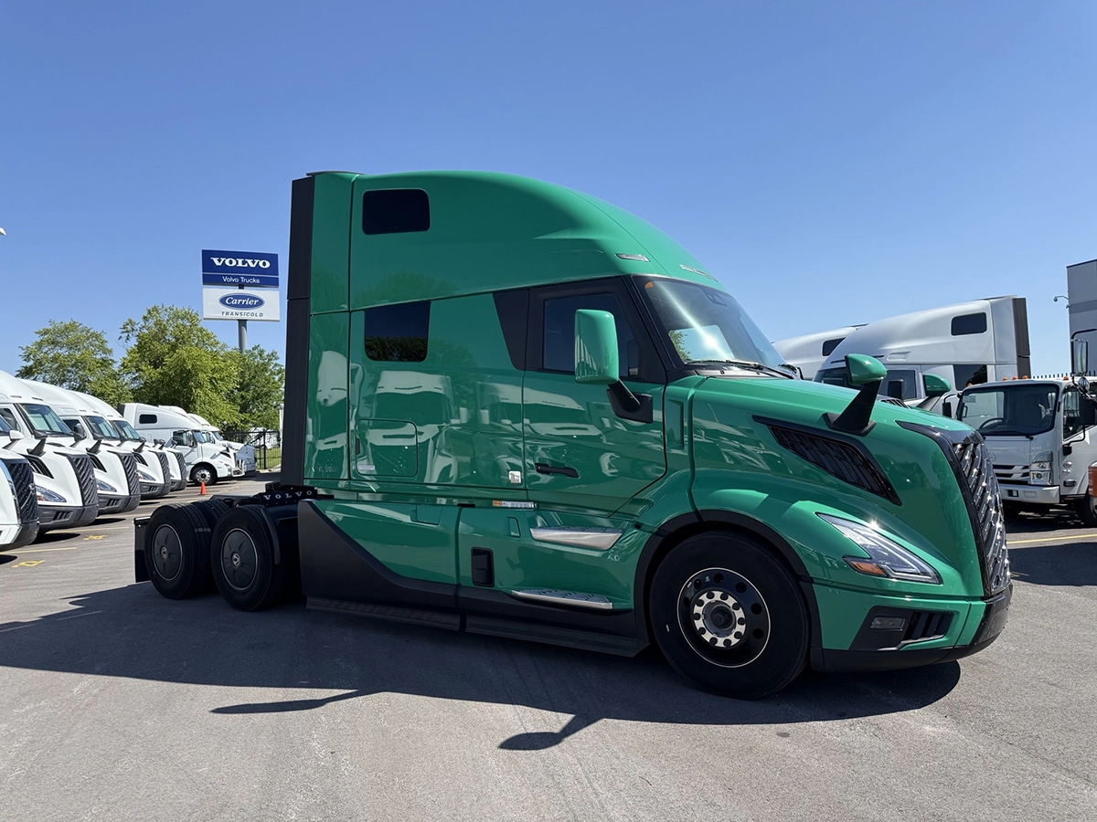 Front passenger side view of a green 2025 Volvo VNL64T860 sleeper semi truck with a high-roof sleeper cab and tandem rear axles.
