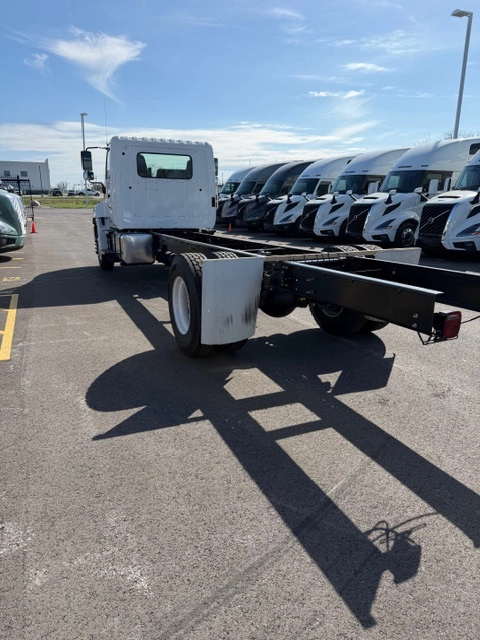 Rear driver side view of a white 2026 Hino L6 cab and chassis truck showing the exposed frame rails, ready for body upfit.