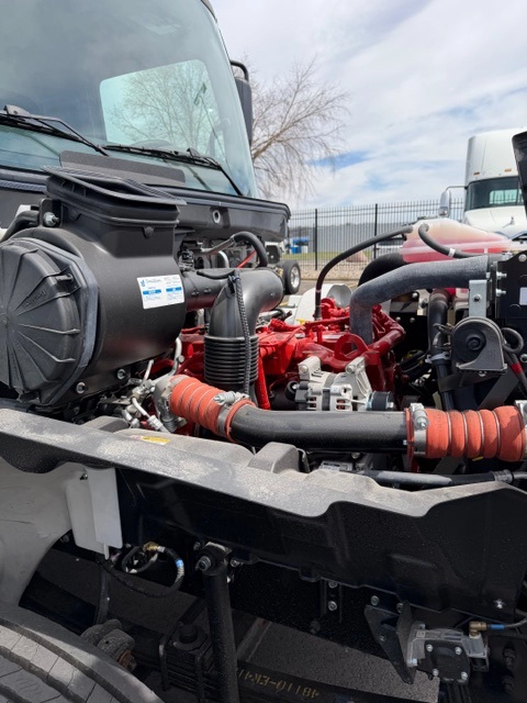 Engine compartment of a 2026 Hino L6 with the hood open, showing the red Cummins diesel engine, air intake, and turbocharger piping.