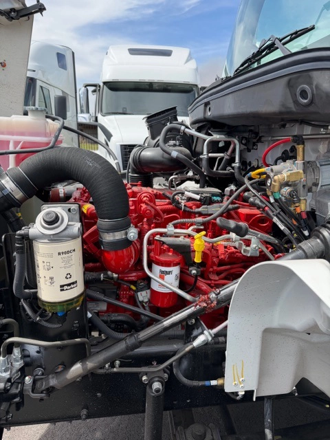 Close-up of the red Cummins diesel engine in a 2026 Hino L6, showing the fuel filter, water separator, and engine wiring.