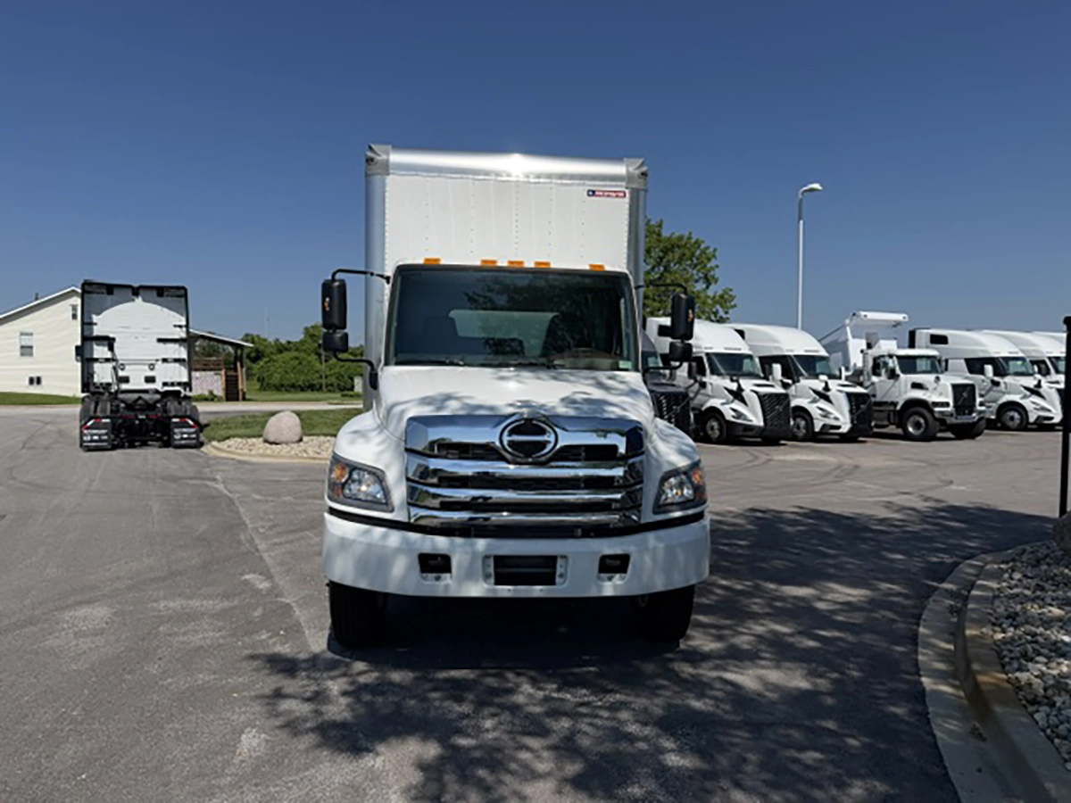 Front view of a white 2026 Hino L6 box truck with a chrome grille, Hino badge, and dual side mirrors.