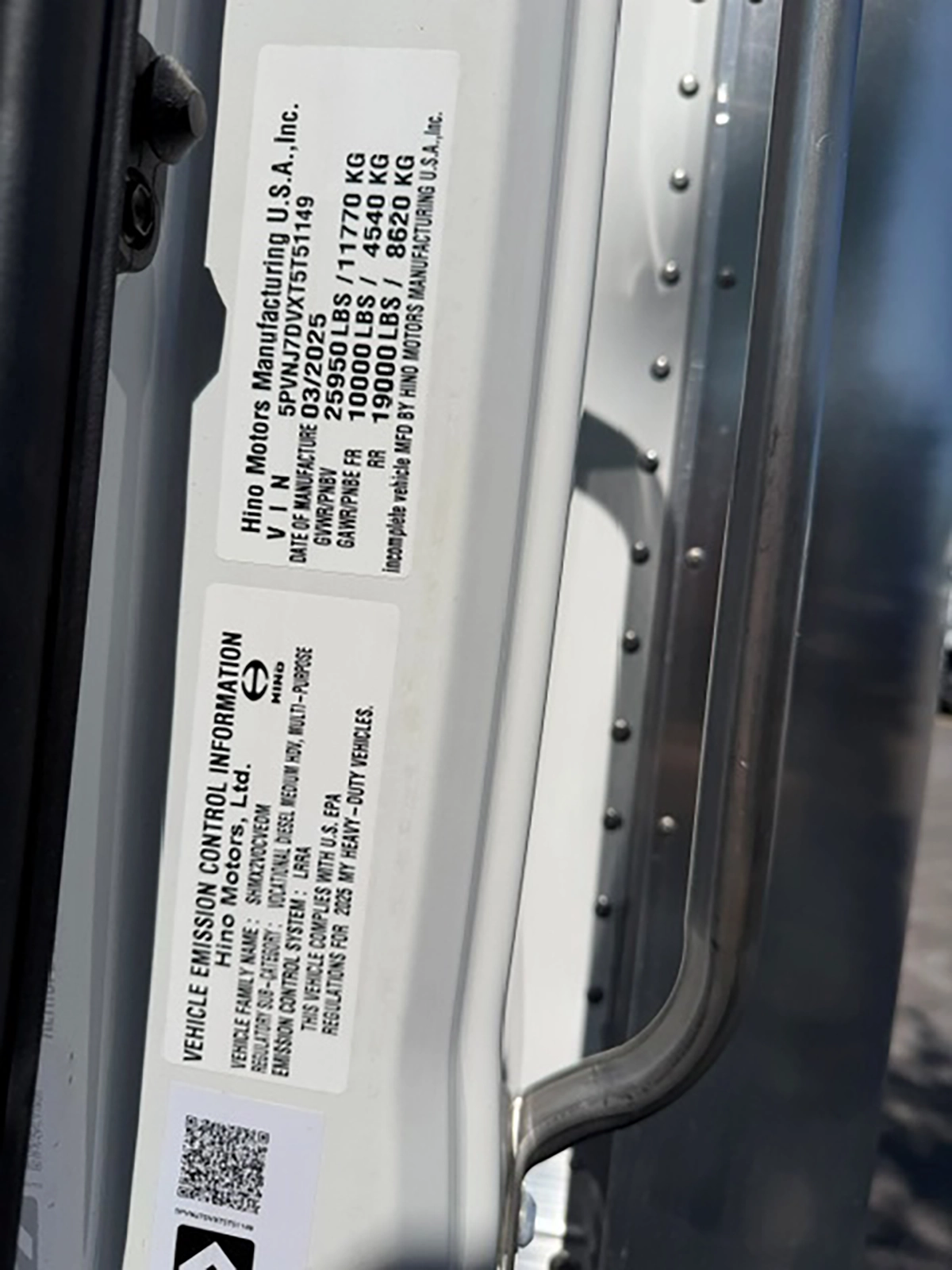 Manufacturer's door jamb sticker on a 2026 Hino L6 showing a GVWR of 25,950 pounds, front and rear axle ratings, and the vehicle identification number.