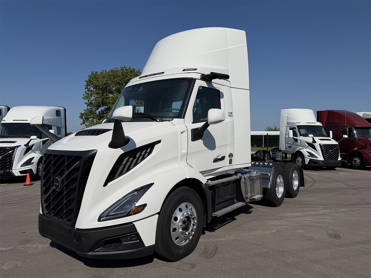 Front driver-side view of a white Volvo VNR 300 day cab truck tractor with tandem rear axles and chrome wheels, parked at Gateway Truck & Refrigeration.
